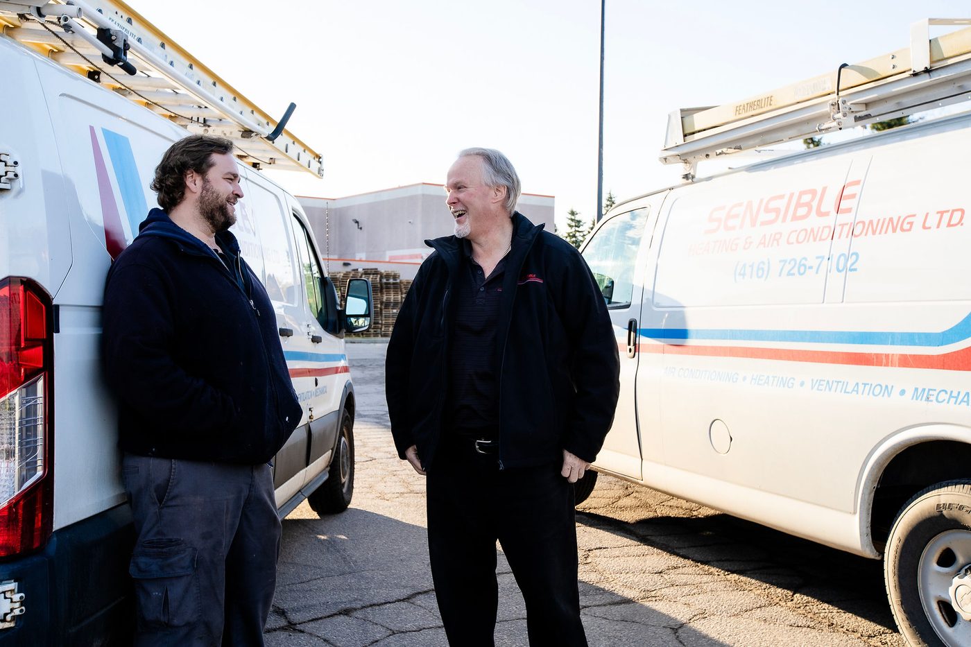 Two Sensible technicians talking beside their service vans